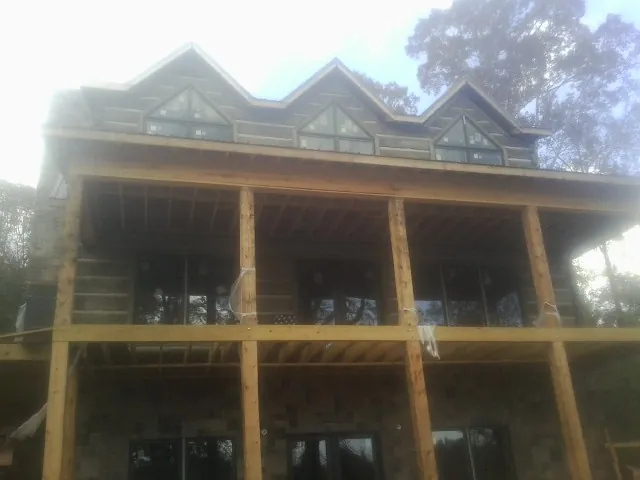 Dormers and porch framing on a large log home under construction — Roof Coating work by our crew in Playa Del Rey