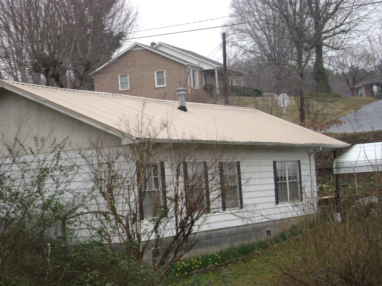 Tan metal roof on a white sided house set into a hillside — Commercial Roofing by Roofing Brothers in Playa Del Rey