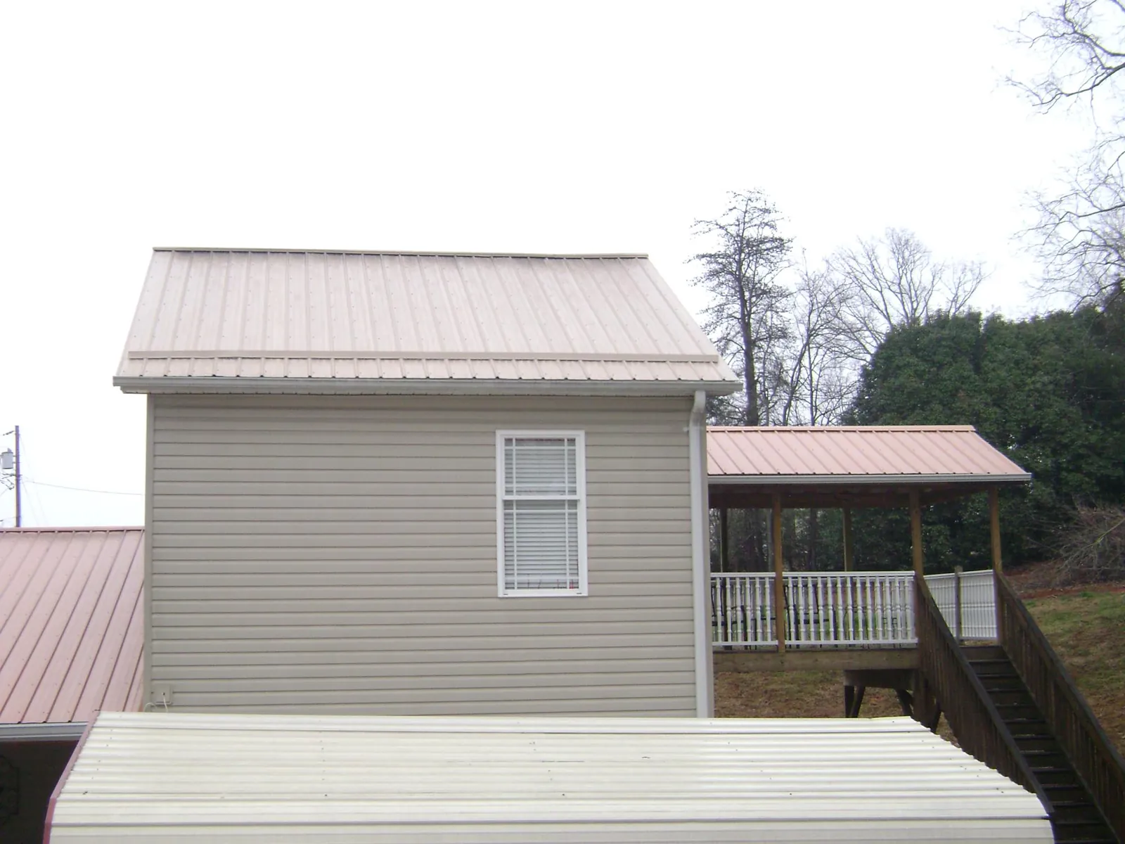 Tan metal roofs on a two story addition and attached porch, from a Roof Replacement job in Playa Del Rey